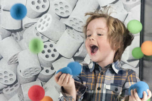Bilde av gutt som ler blant blant fargerike baller som flyr i luften