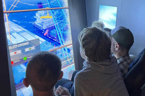 Barn som styrer skip med skipssimulator.