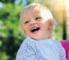 Litet barn som smiler ute om sommeren.