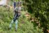 Bilde av gutt som tar zip-line i grønn skog.