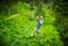 Bilde av jente som tar zip-line i grønn skog.