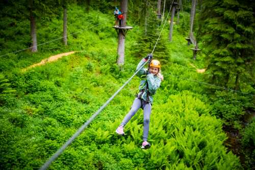 Bilde av jente som tar zip-line i grønn skog.