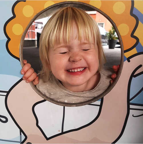 Bilde av jente i fotovegg som lager morsomt ansikt.